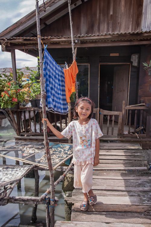 Free A smiling girl stands on a wooden dock in North Sumatra, Indonesia. Stock Photo