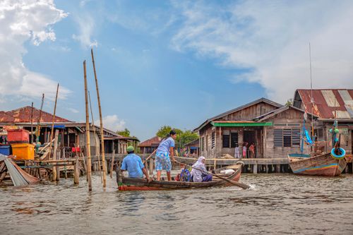 Free Residents of a North Sumatra waterfront village navigate wooden boats in a serene rural setting. Stock Photo