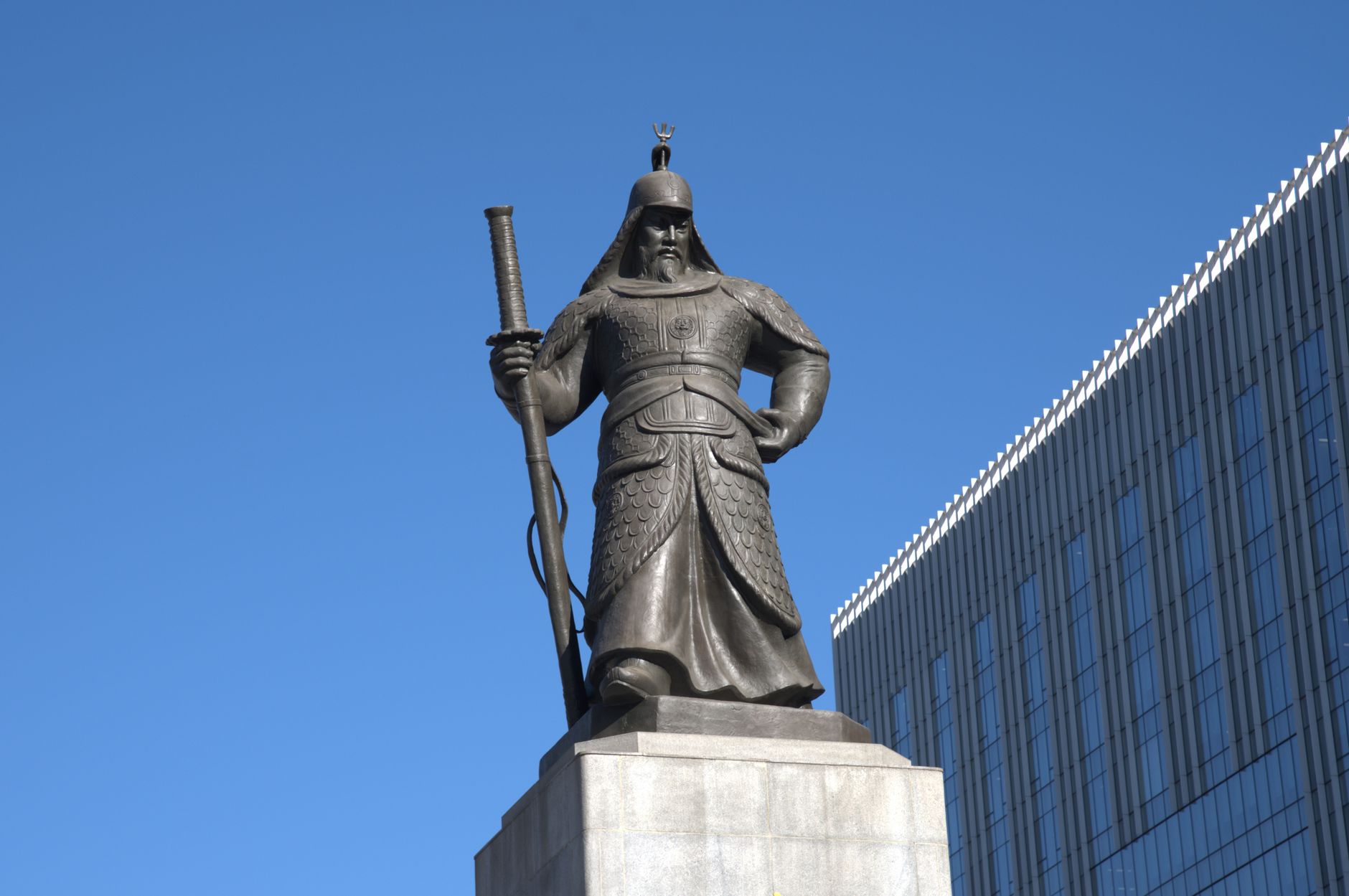 The iconic statue of Admiral Yi Sun-sin stands prominently in Seoul under a clear blue sky.