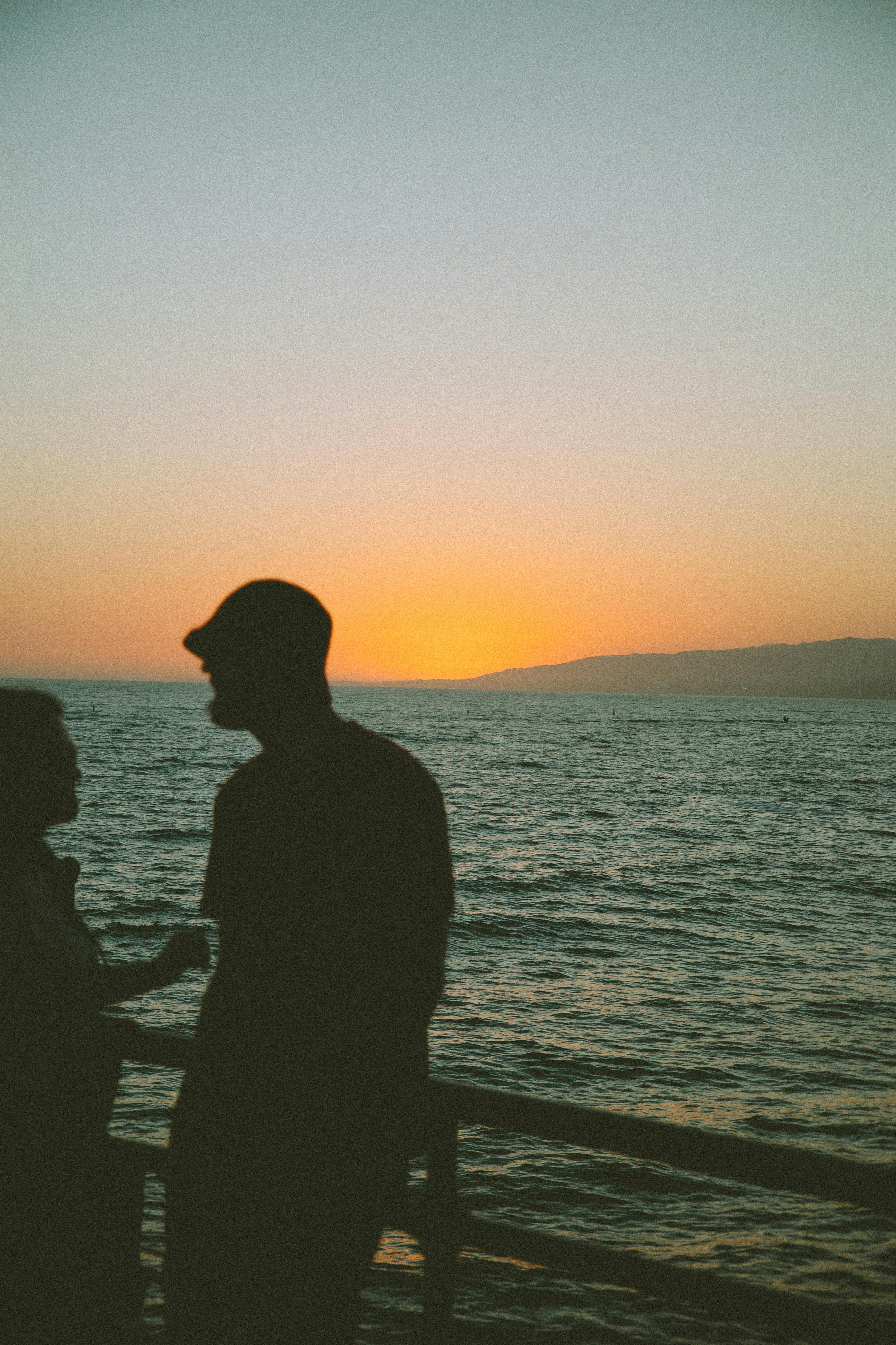Gratis Figure in silhouette contro un vivace tramonto sull'oceano a Los Angeles. Foto a disposizione