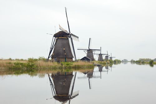 Free Historic windmills reflected in the serene waters of Kinderdijk, South Holland, Netherlands. Stock Photo