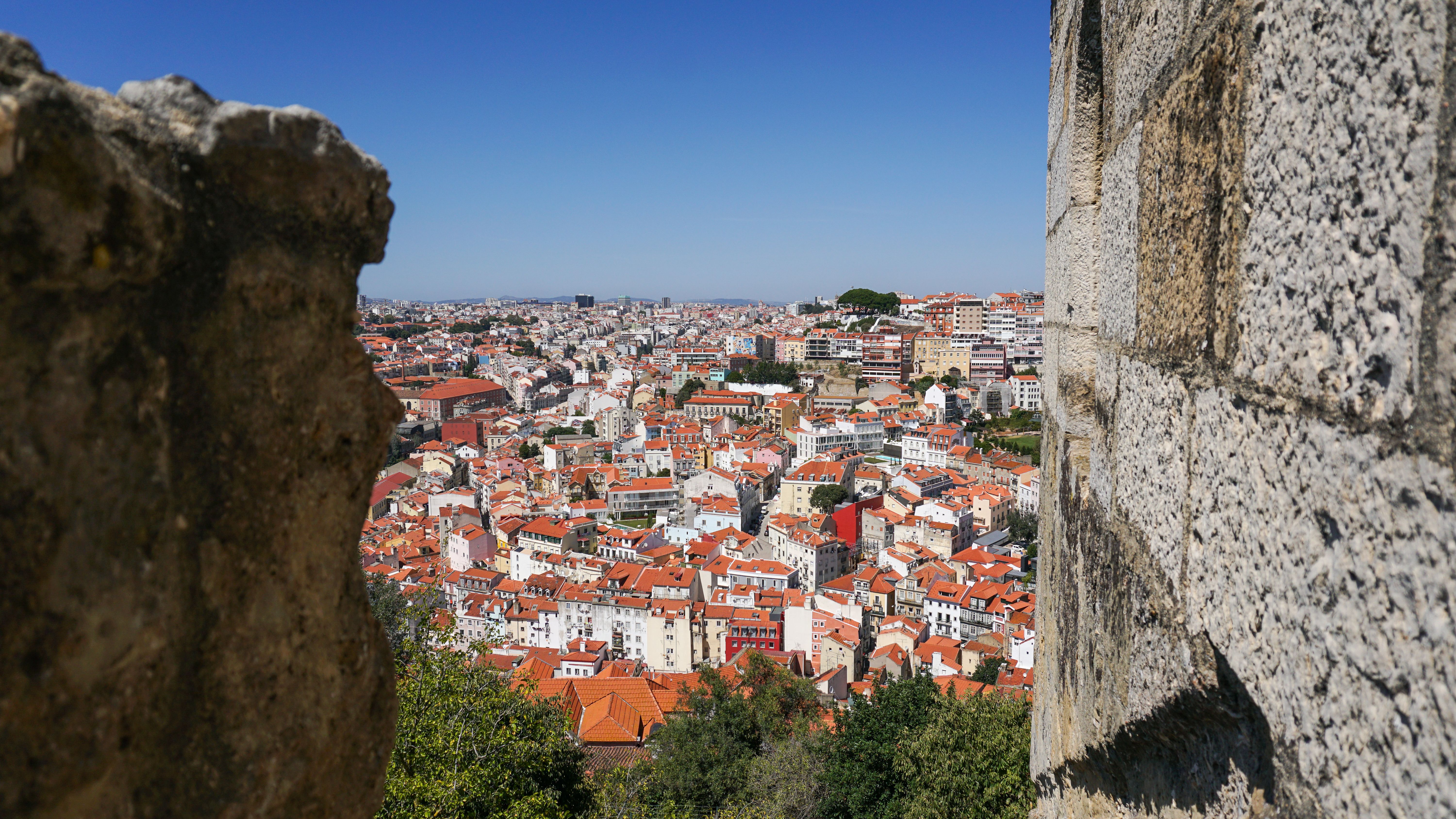 A breathtaking view of Lisbon's red rooftops captured from historic castle walls on a sunny day.