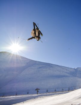 A daring skier performs a mid-air trick against a bright blue winter sky, showcasing extreme sport skills.
