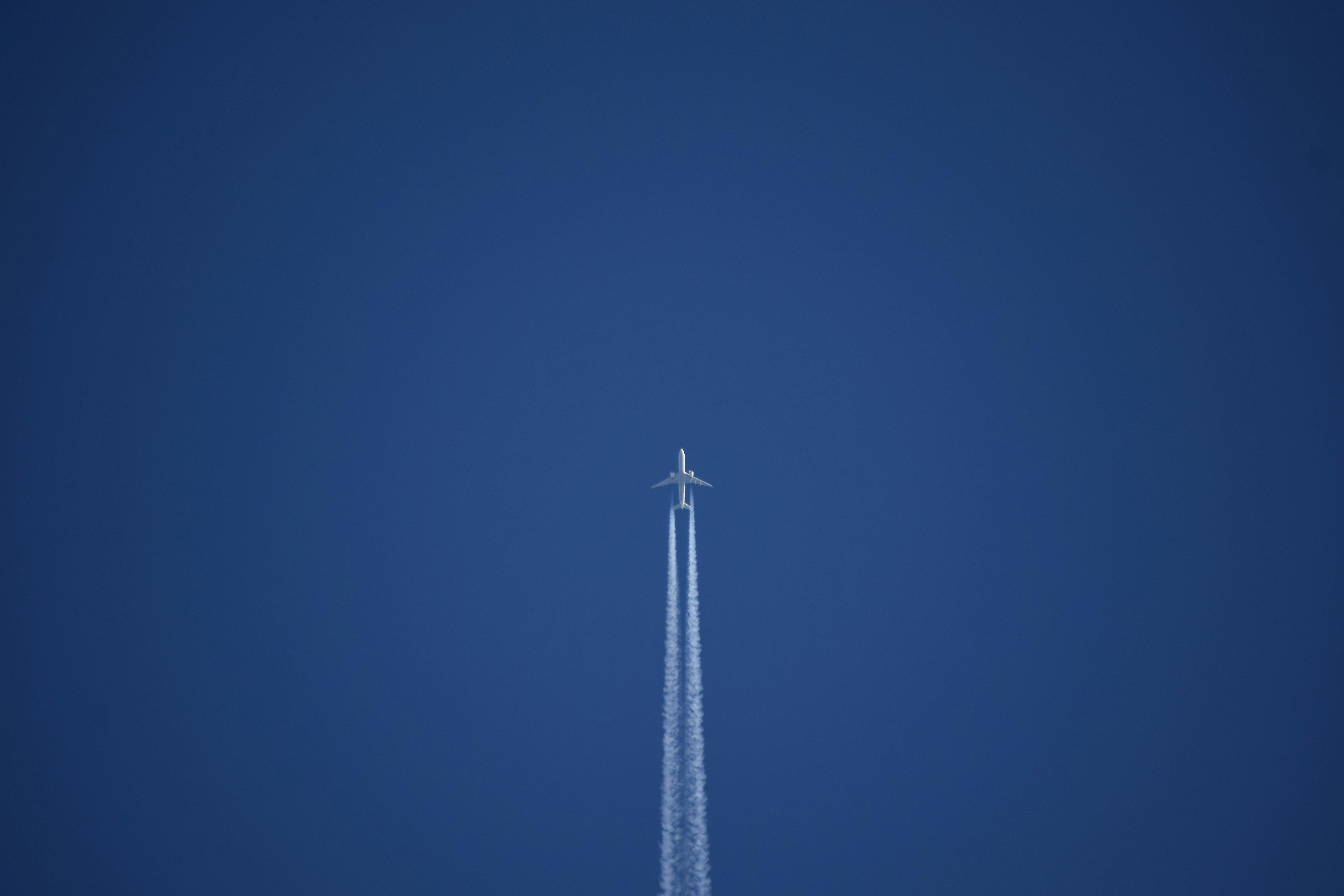 Free Airplane soaring through a clear blue sky leaving a distinct vapor trail behind. Stock Photo