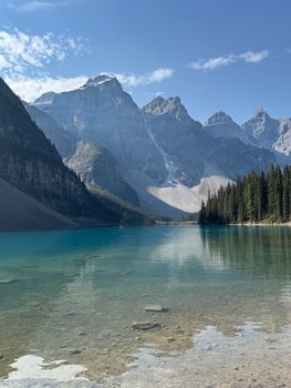 Clear turquoise waters of Moraine Lake with the backdrop of the Canadian Rockies under a bright sky.