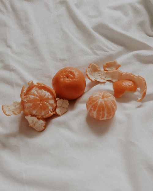 Free Minimalist image of peeled tangerines and peels on white fabric, showcasing vibrant orange color contrast. Stock Photo
