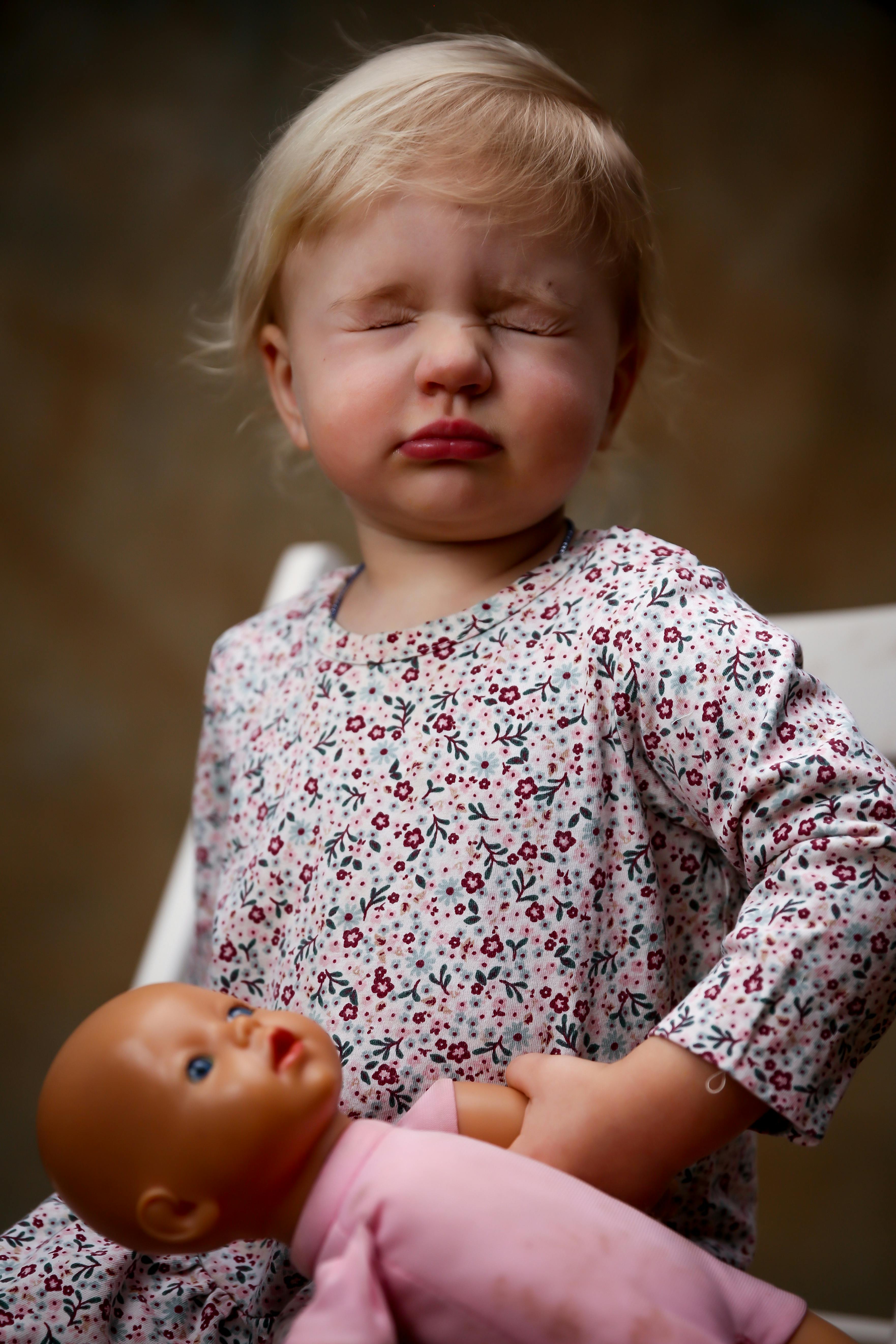 toddler wearing floral dress holding doll