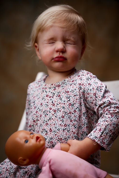 Free Toddler Wearing Floral Dress Holding Doll Stock Photo