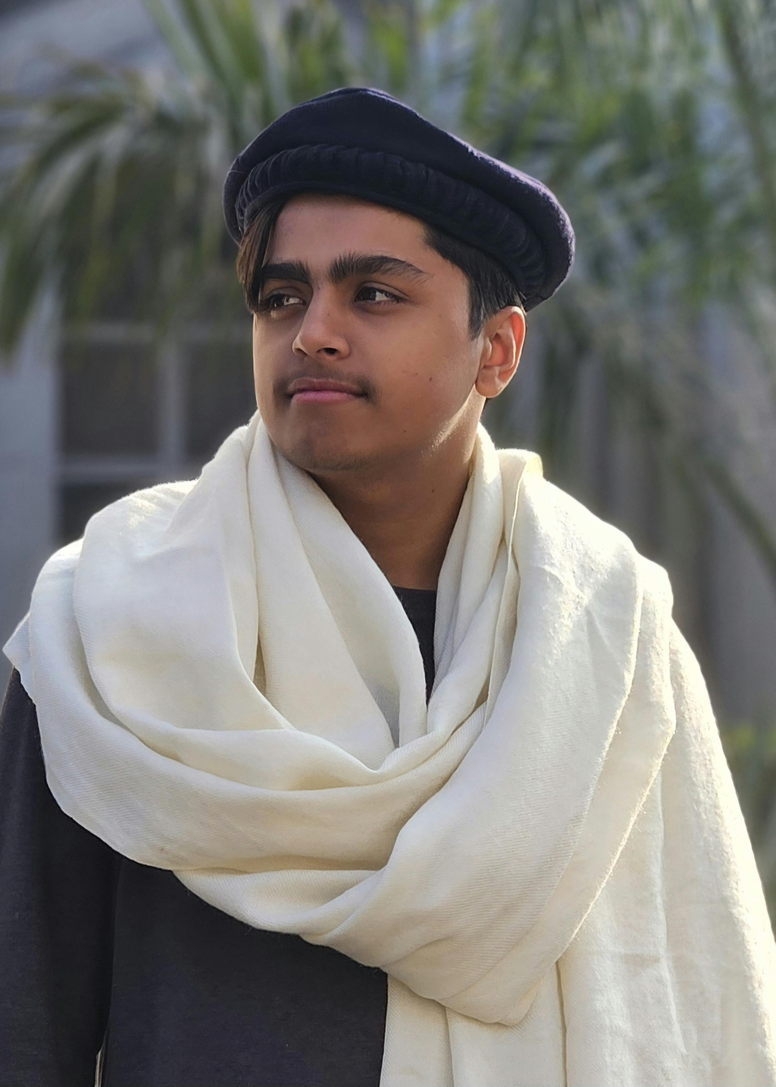 Portrait of a young man wearing traditional clothing and cap outdoors.