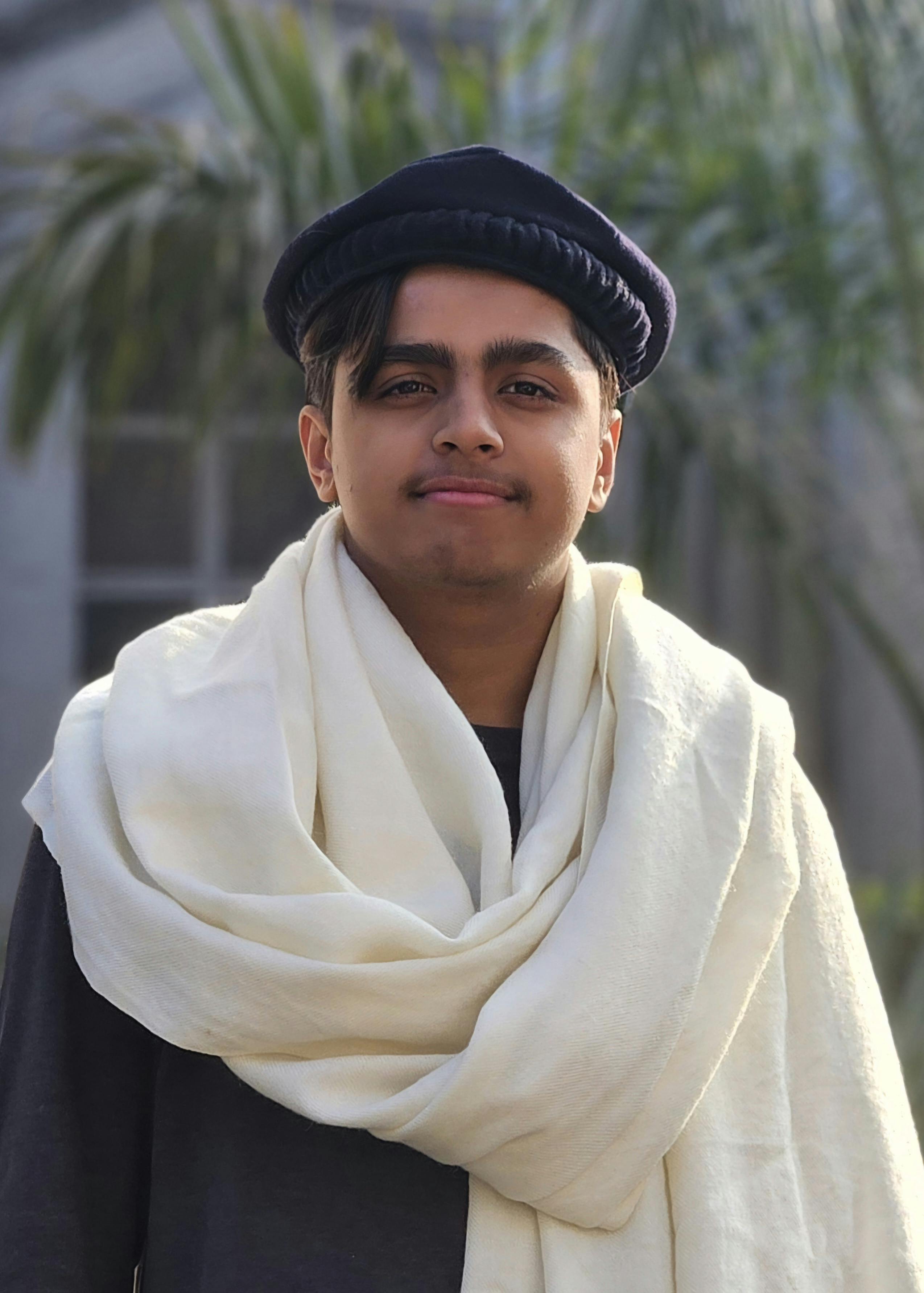 Portrait of a young man wearing traditional attire with a serene expression outdoors.
