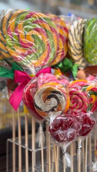 Vibrant spiral lollipops on display outdoors, wrapped in plastic and tied with ribbons.
