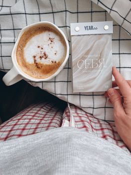 A cozy scene of a cappuccino and an inspirational note on a plaid background.