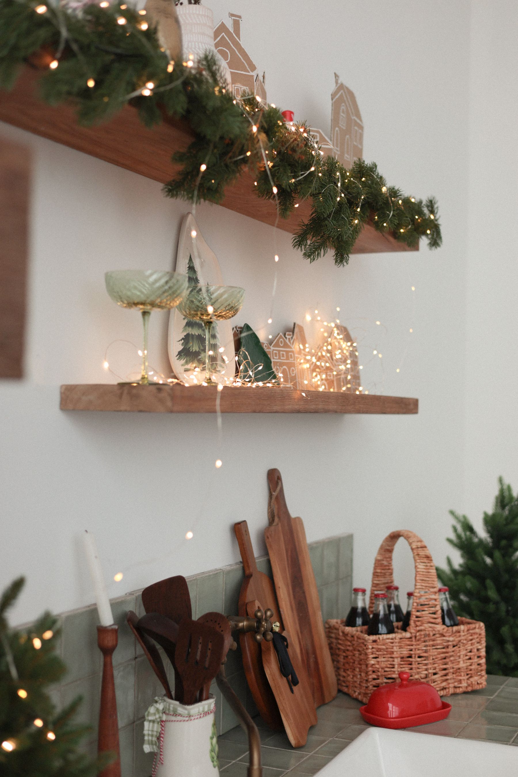 Kitchen shelving decorated with warm festive lights and greenery