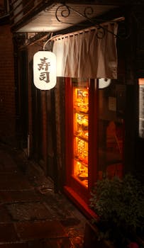Warmly illuminated entrance of a sushi restaurant in Shrewsbury, England, showcasing Asian architecture and ambiance.