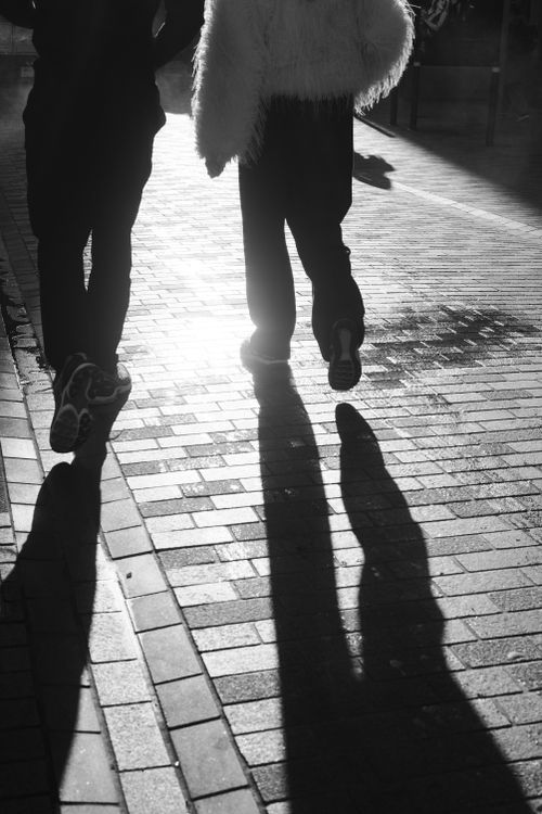 Free Black and white street scene with shadows of walking people on cobblestone path in Dublin. Stock Photo