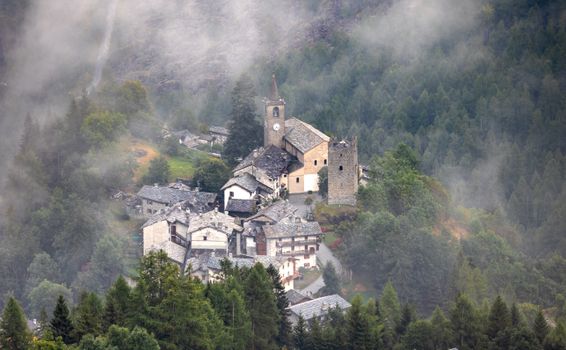 Aerial view of a charming Italian village surrounded by fog and lush greenery.