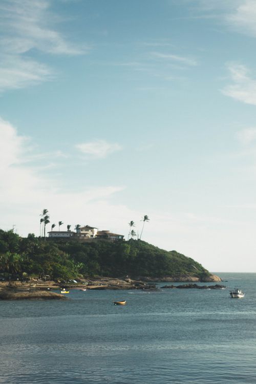 Free Tranquil coastal scene with boats, lush greenery, and a clear blue sky. Stock Photo