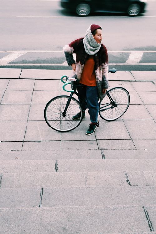 Free Stylish person standing with a bicycle on an urban pavement, capturing modern city life in St. Petersburg. Stock Photo