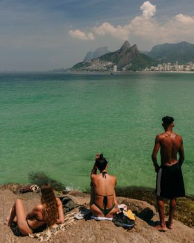 People enjoying a sunny day at Arpoador Beach, Rio de Janeiro, Brazil.