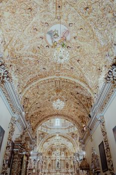 Intricate Baroque architecture inside a historic cathedral with a richly decorated ceiling and chandeliers.