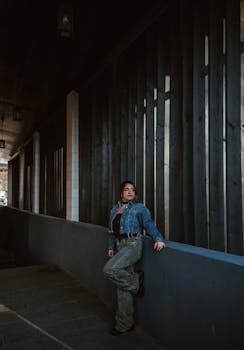 Woman in denim jacket poses stylishly against a dark wooden wall in Cluj-Napoca.