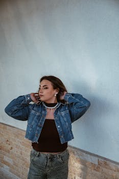 Portrait of a fashionable woman in a denim jacket against a wall in Cluj-Napoca, Romania.