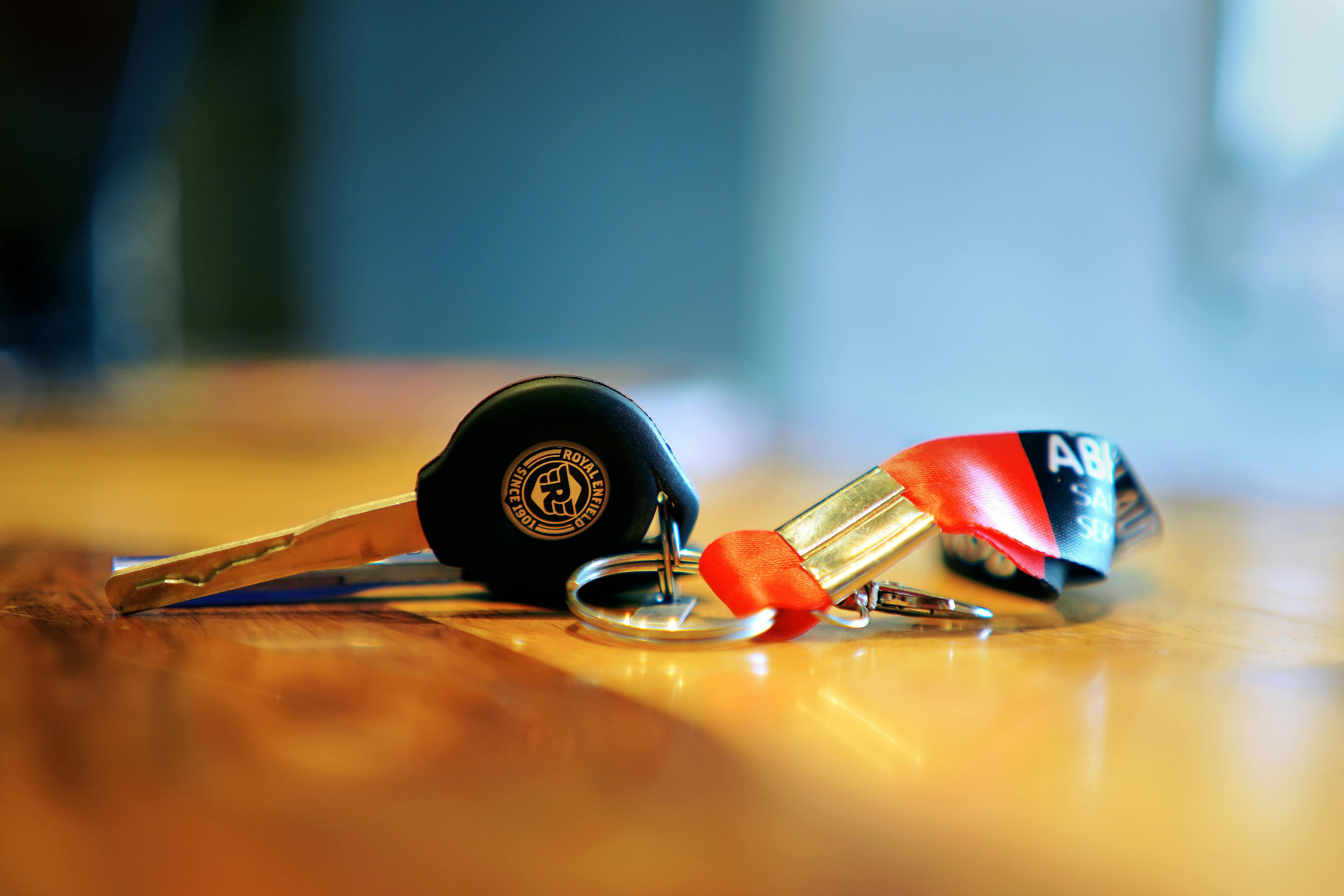 A detailed photo of a Royal Enfield motorcycle key on a wooden surface with warm lighting.