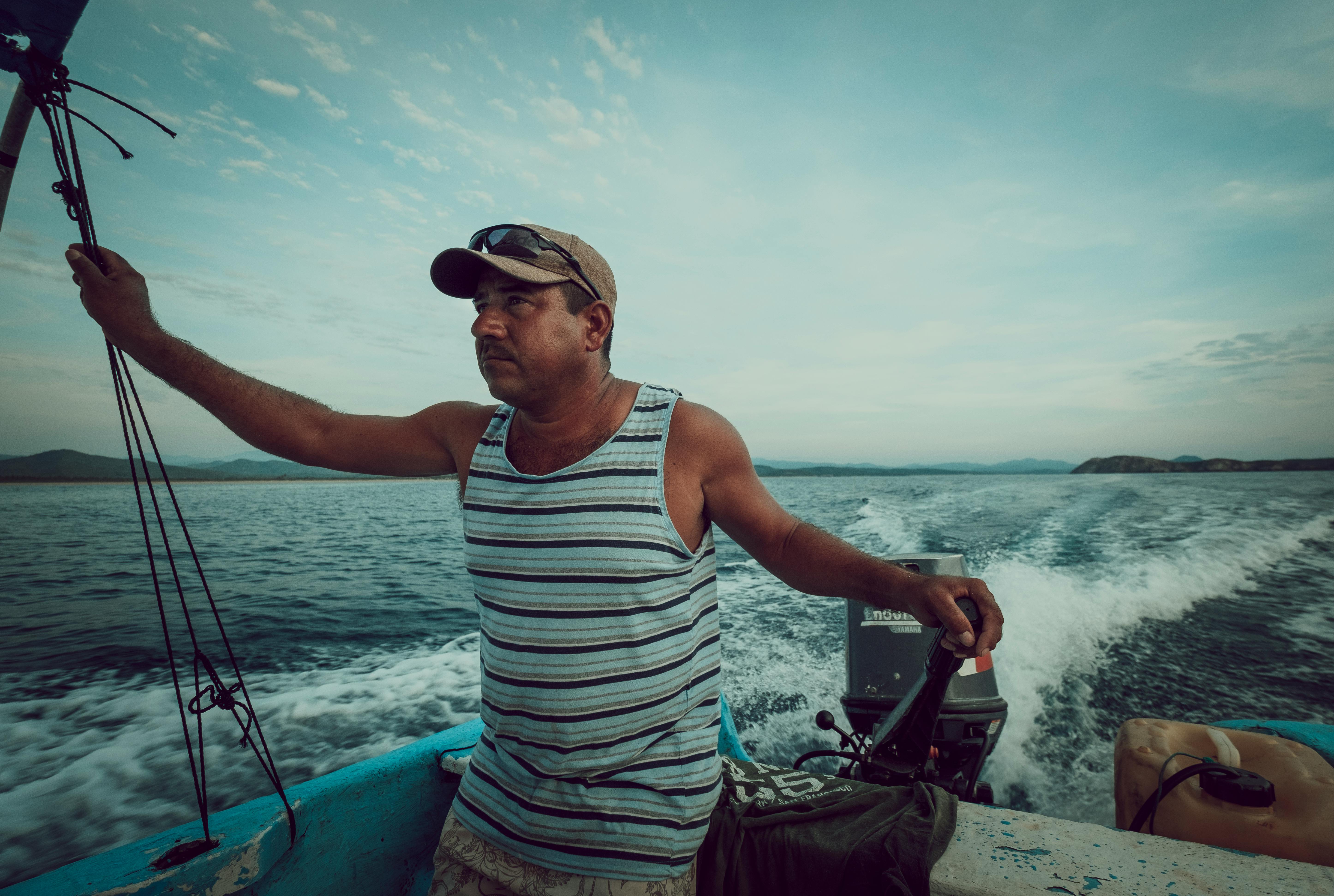 A man confidently steering a motorboat on the open sea under a clear sky, adventure and freedom.