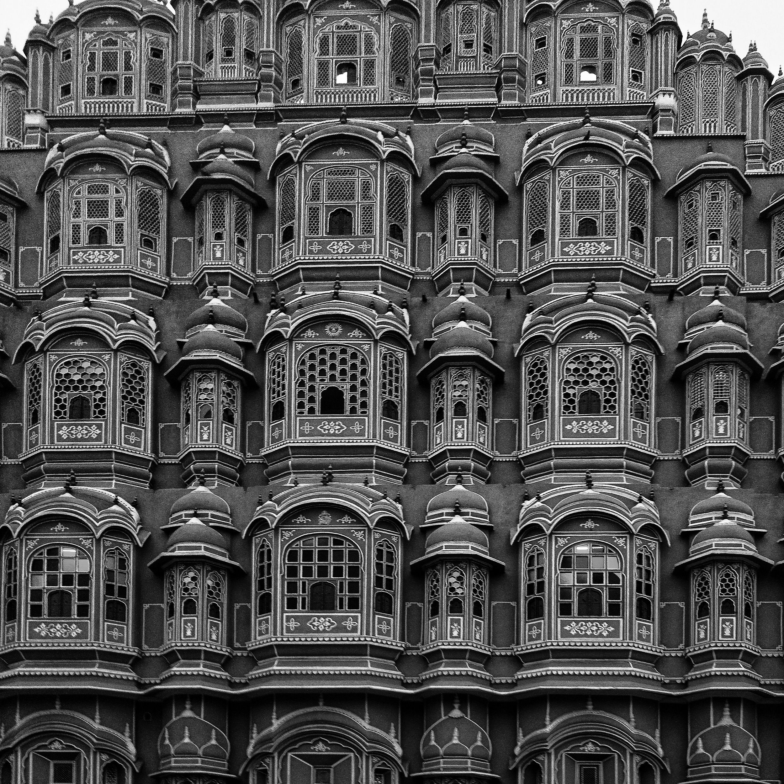 Black and white photo of the detailed facade of Hawa Mahal, Jaipur, showcasing intricate architecture.