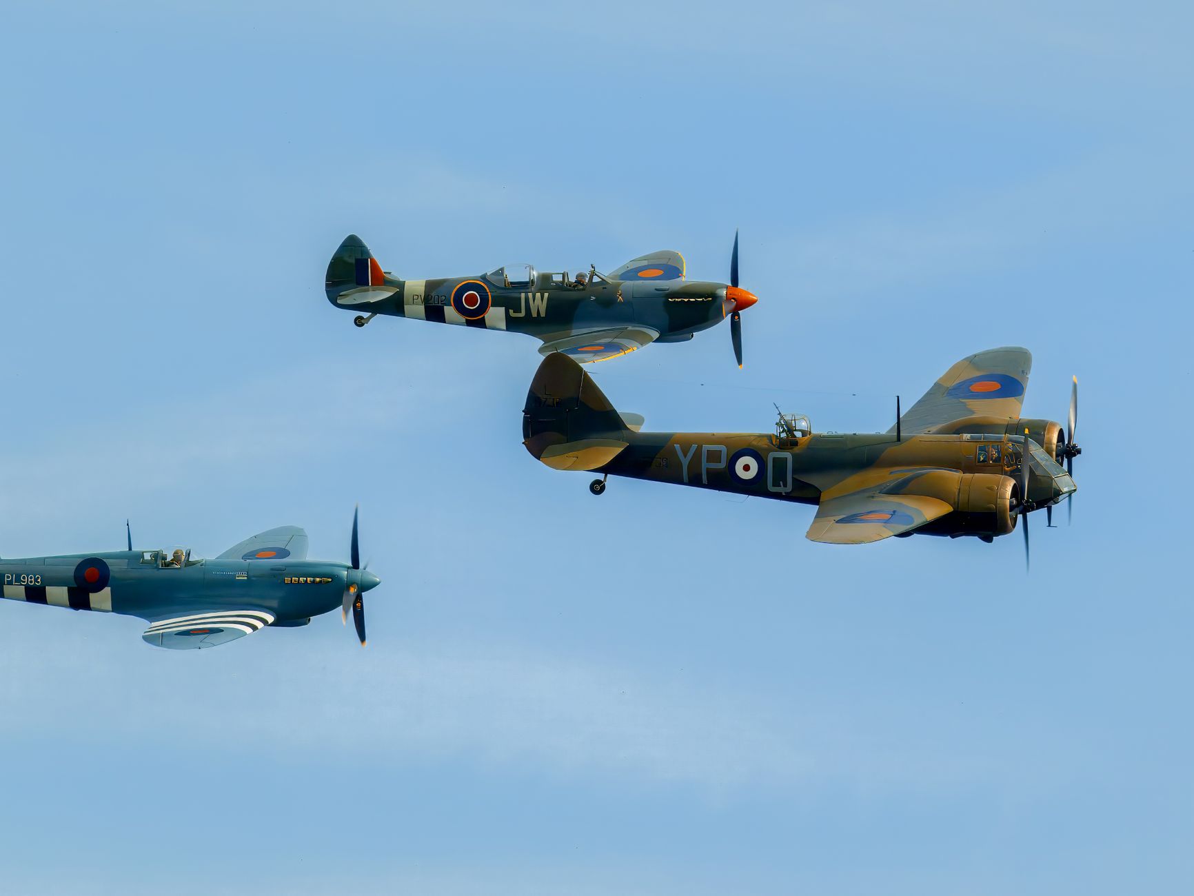 A stunning image of three vintage WWII fighter planes against a clear blue sky, showcasing historic aviation.