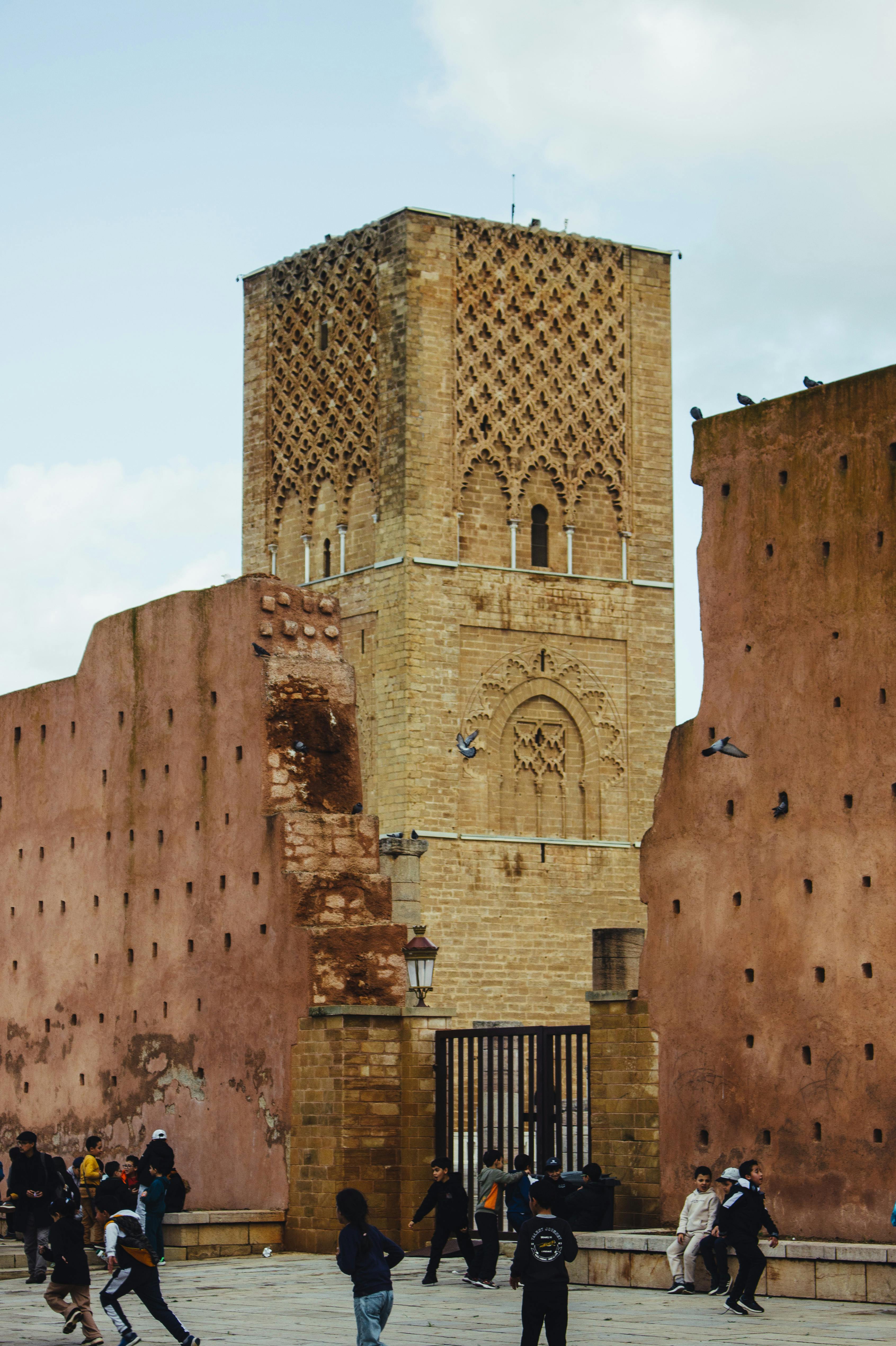 View of the Hassan Tower with people in Rabat, Morocco, highlighting its historical architecture.