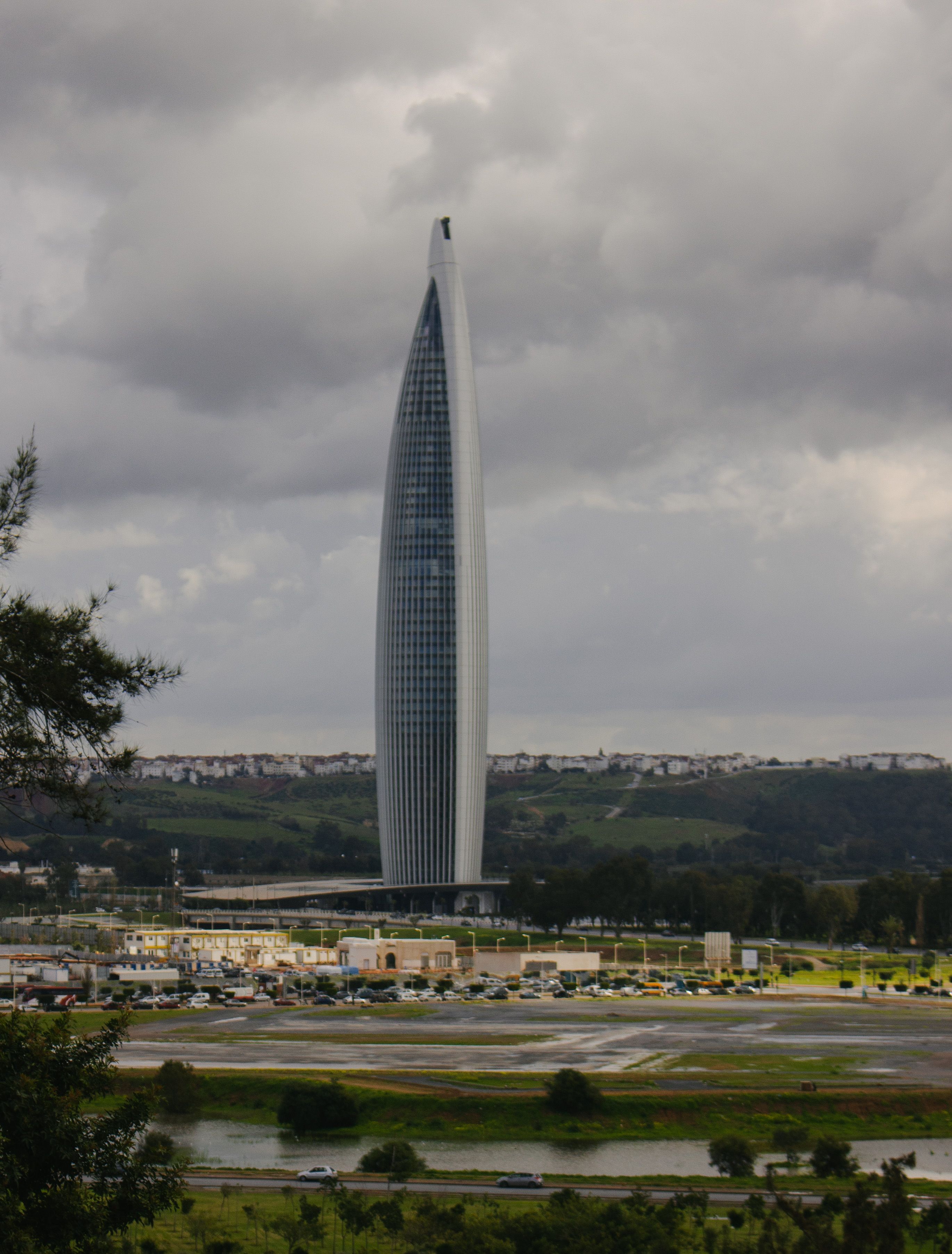 A modern skyscraper stands tall under a cloudy sky, an iconic architectural marvel in a cityscape.