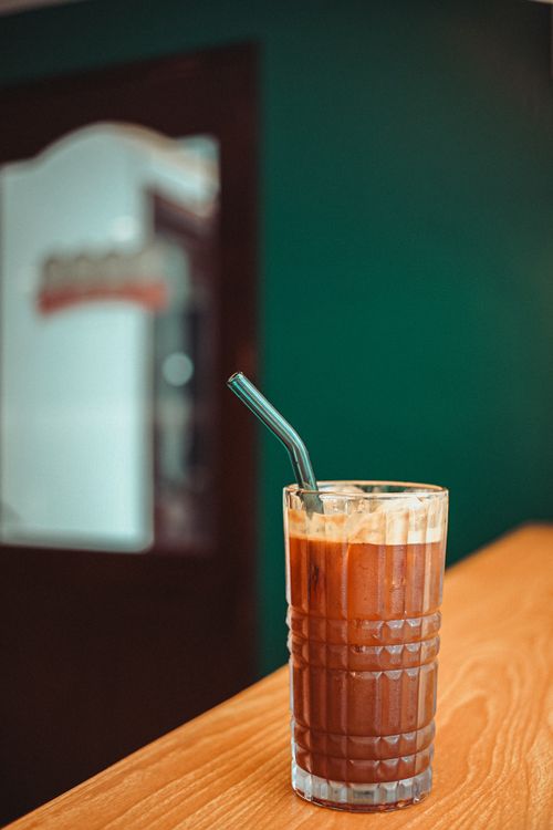 Free Close-up of iced coffee with straw on wooden table indoors, perfect for refreshment and cafe themes. Stock Photo