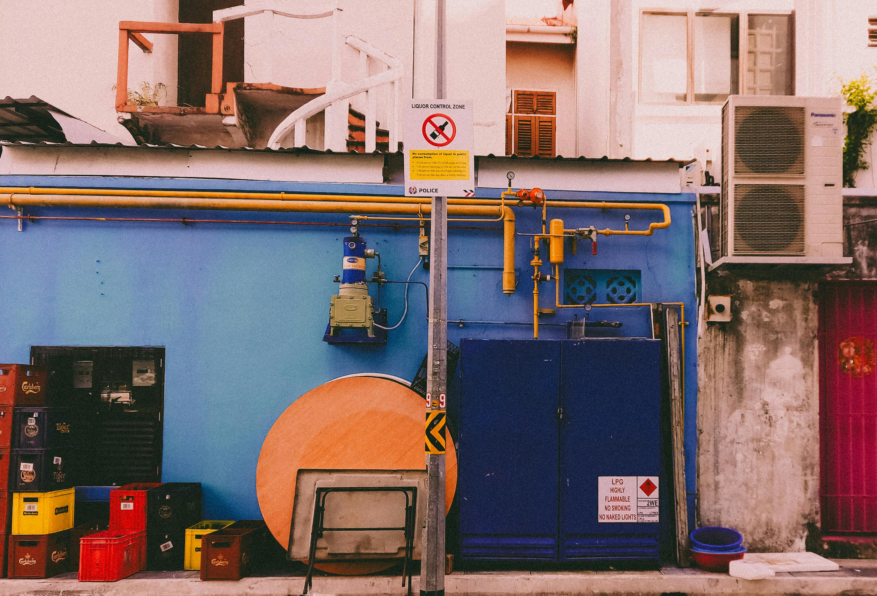 бесплатная Оживлённый городской переулок с разноцветными распределительными коробками и трубами на синей стене. Стоковое фото