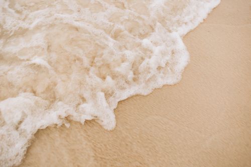 Free A serene wave washes over a sandy beach creating a peaceful and calming scene. Stock Photo