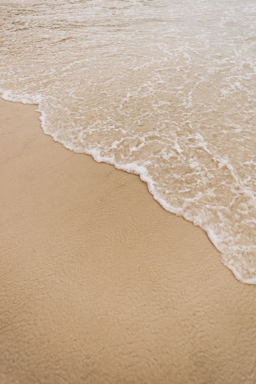 Free Tranquil image of a gentle wave meeting a sandy beach provides a calming coastal vibe. Stock Photo