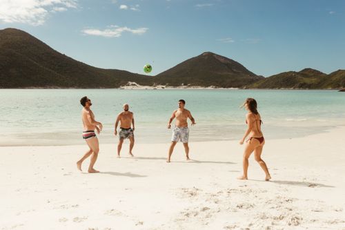 Free Group of friends enjoying a beach volleyball game on a sunny tropical beach. Stock Photo