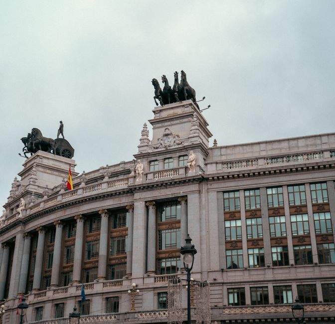 Edificio histórico con estatuas de caballos en el tejado en Madrid, mostrando arquitectura clásica.