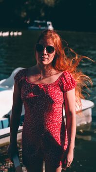 A woman in a red dress enjoys a sunny day by the lake in Buenos Aires.