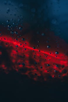 Close-up of water droplets on glass with a red and blue abstract background.