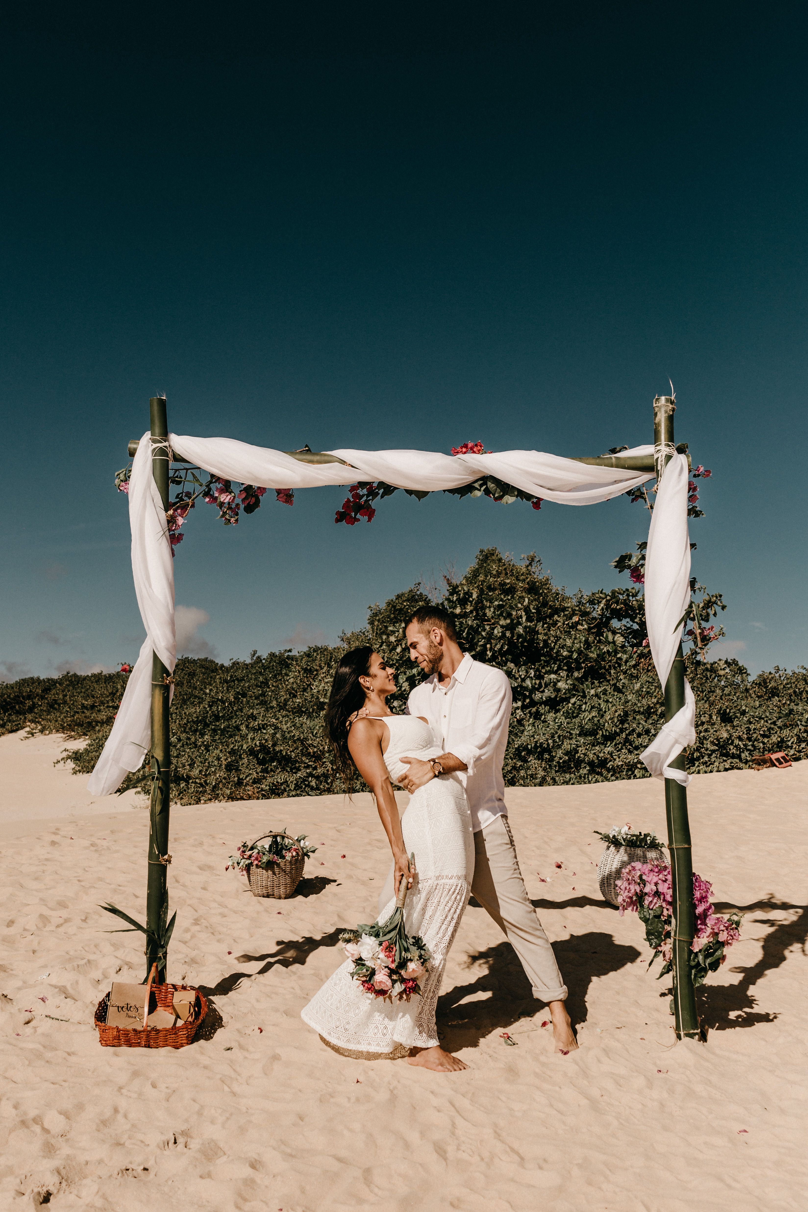 Mariage au Mexique : couple sous une arche de bambou fleurie sur une plage tropicale
