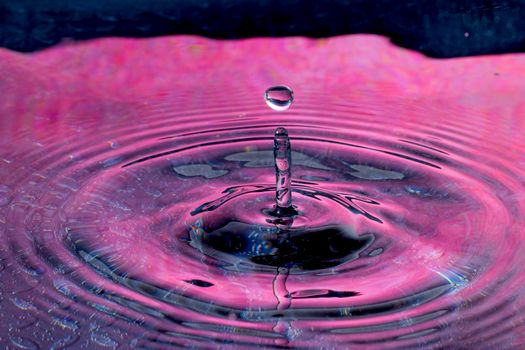 High-speed photo of vibrant water droplet creating colorful ripple effect.