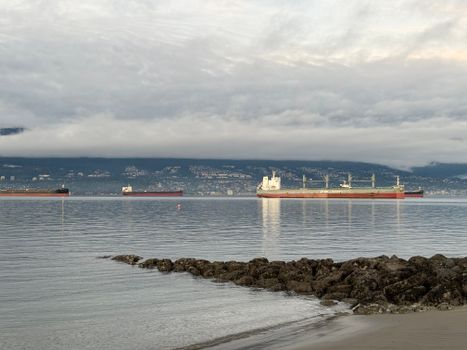 Serene view of cargo ships in Vancouver with calm waters and distant mountains.
