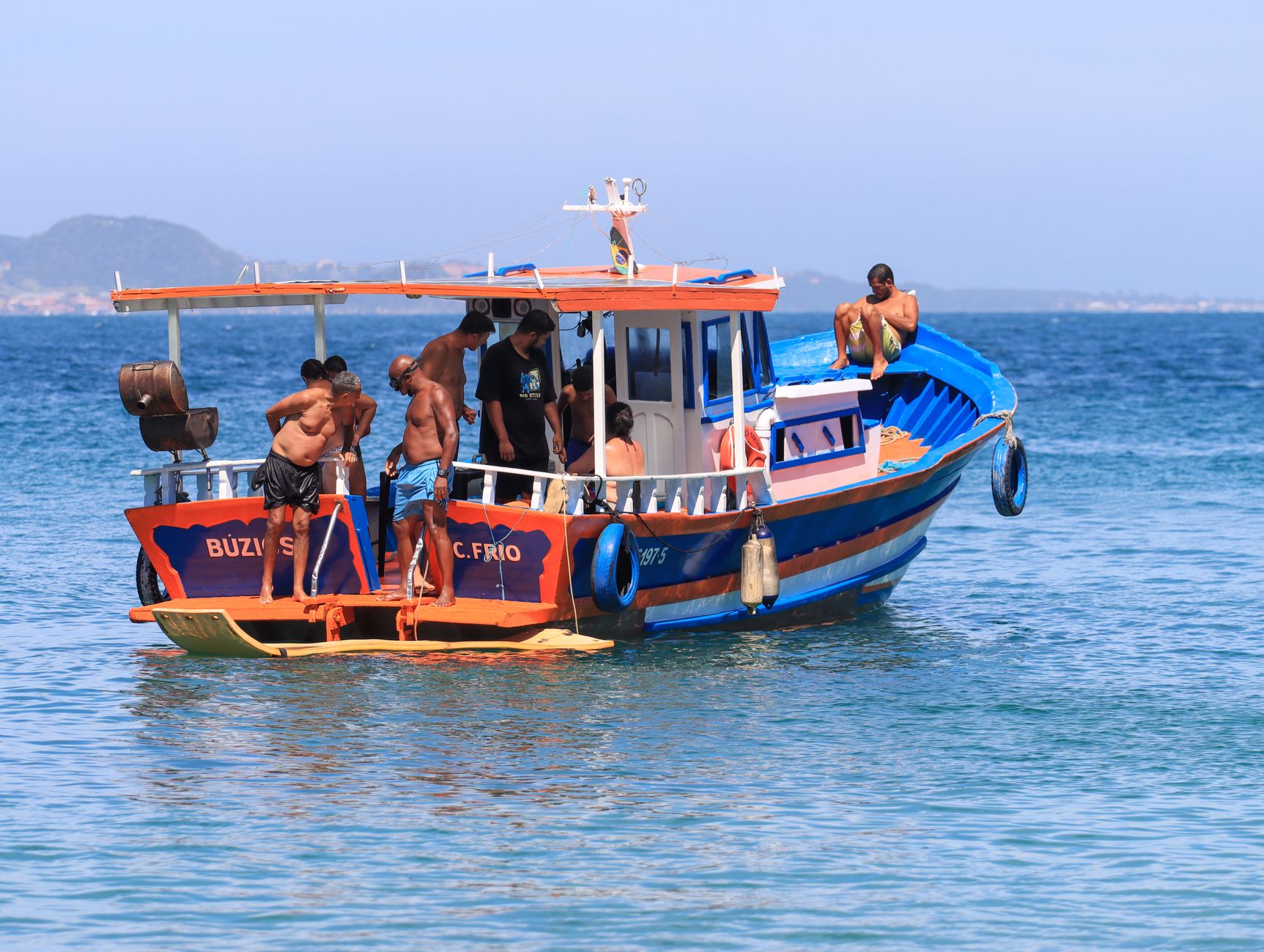 Vibrant fishing boat with passengers enjoying a sunny day on clear Brazilian waters.