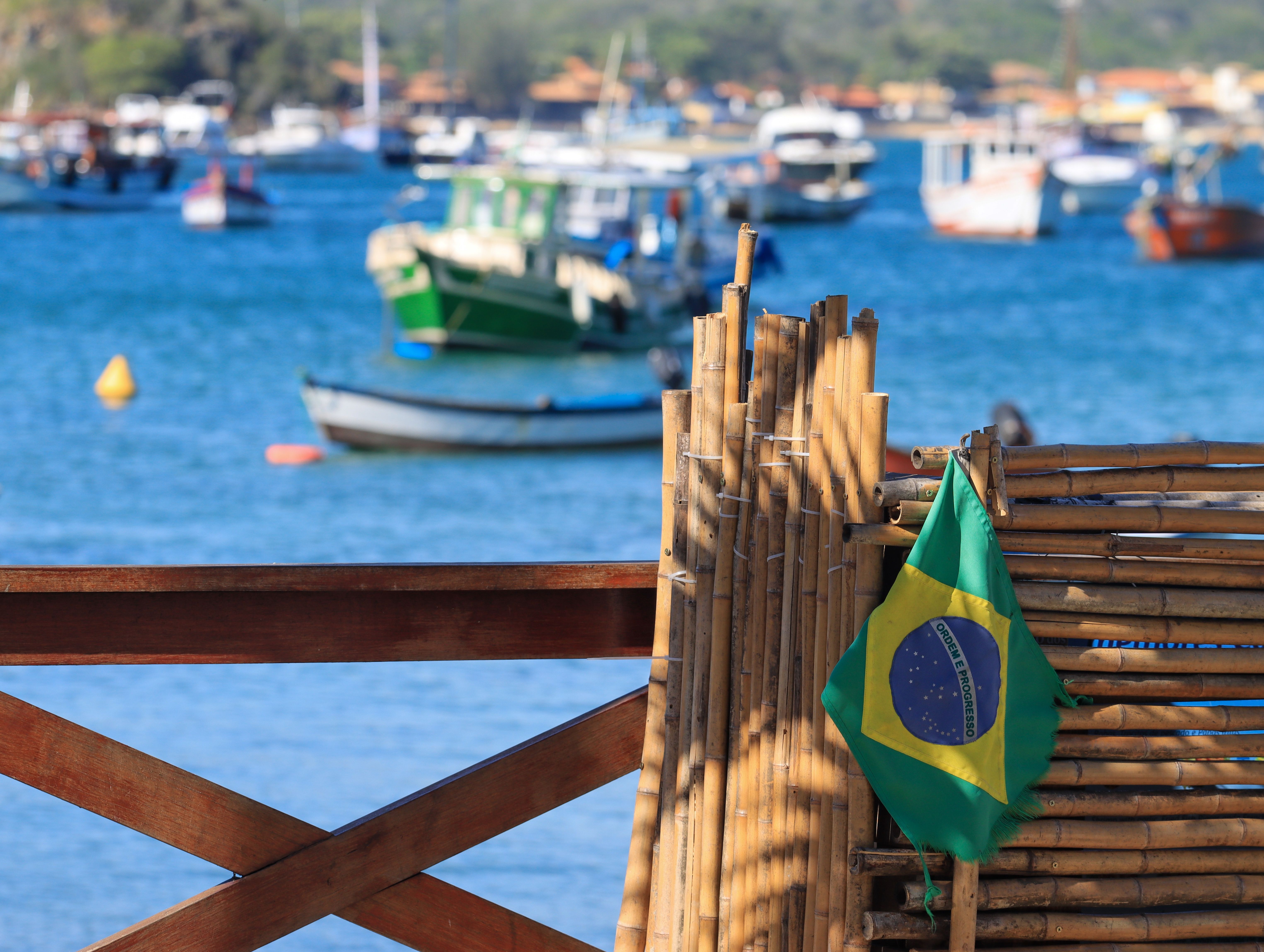 View of a Brazilian flag with boats in a bay, capturing coastal charm and nautical themes.