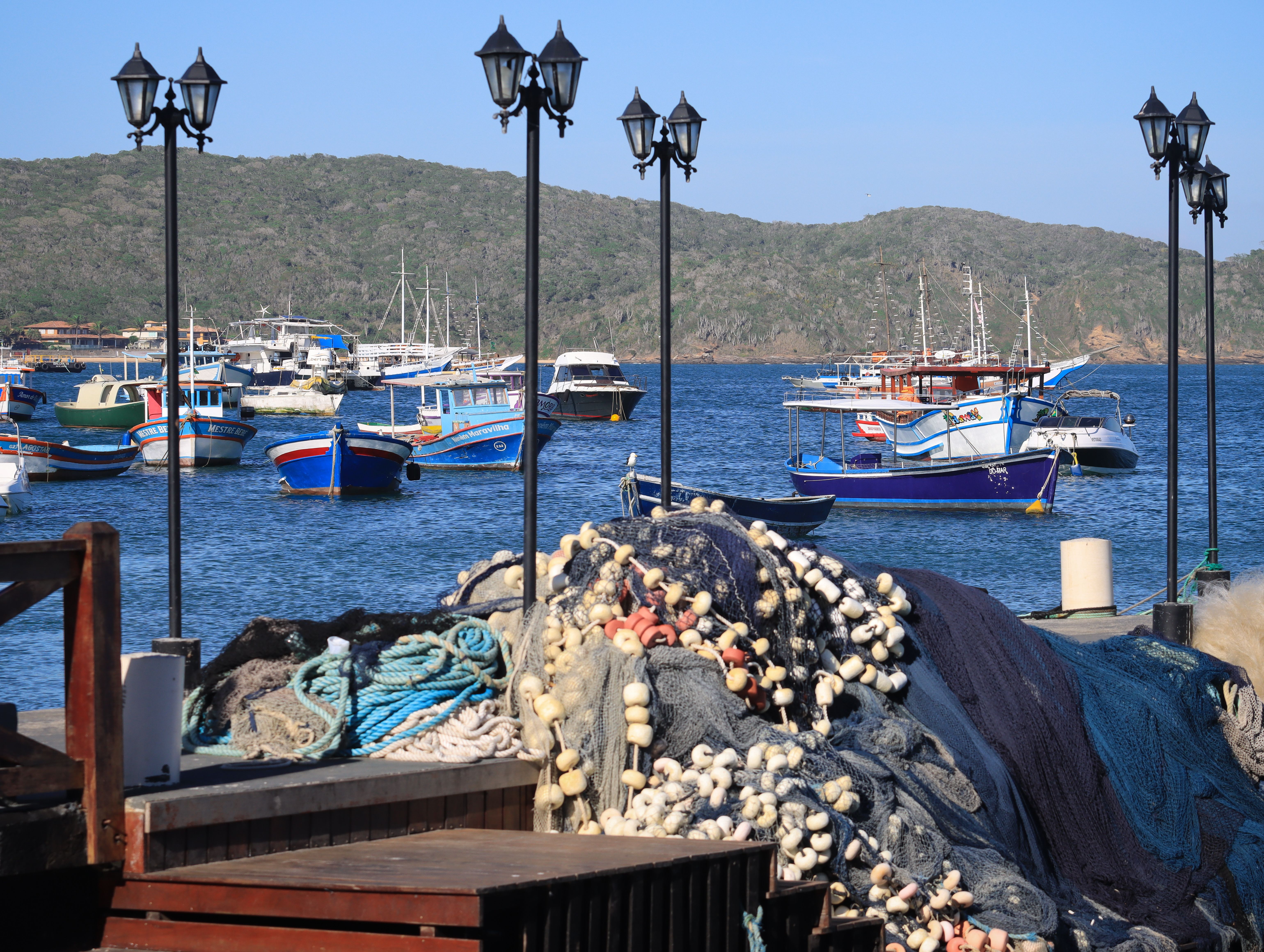 Tranquil harbor scene with colorful fishing boats and nets, ideal for depicting coastal life.