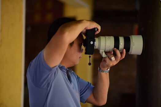 A focused photographer using a telephoto lens to capture a perfect shot.