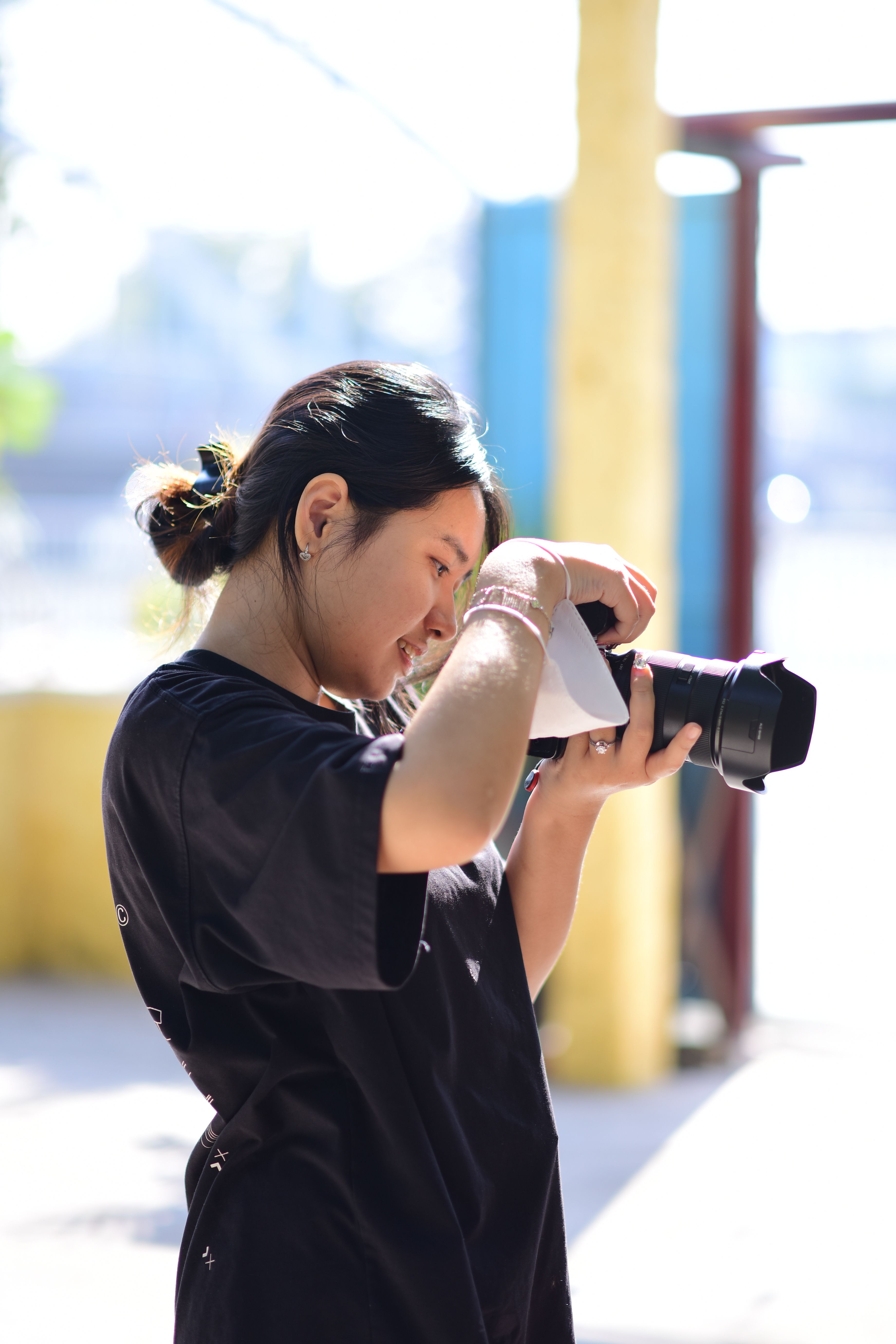 A focused young adult photographing outdoors, utilizing natural light.