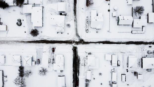 Aerial shot of suburbia blanketed in fresh snow during daytime.