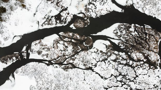 从鸟瞰图看，冬季冰雪覆盖的河流呈现出复杂的图案，犹如抽象艺术